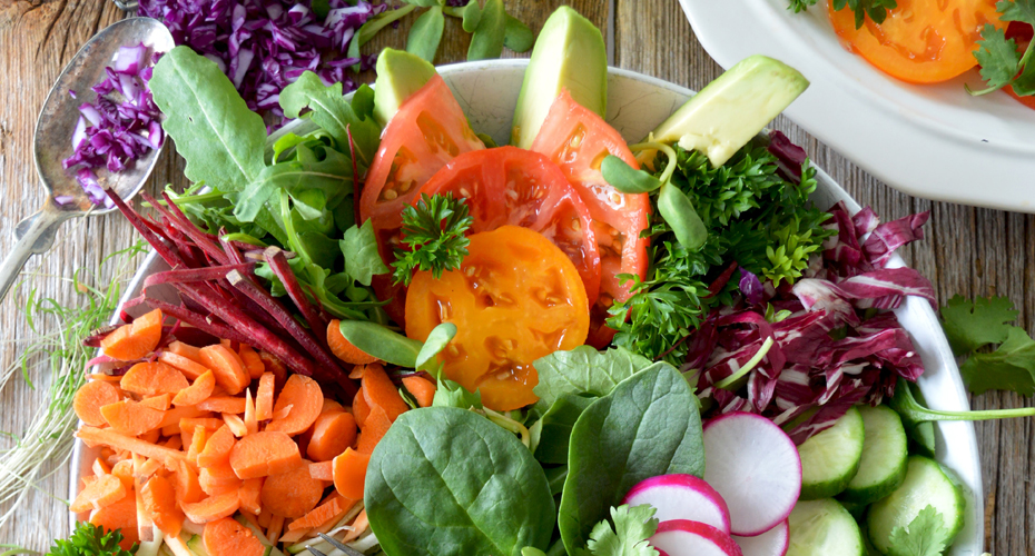 A plate of prepared vegetables including tomatoes, spinach, radishes and carrots.